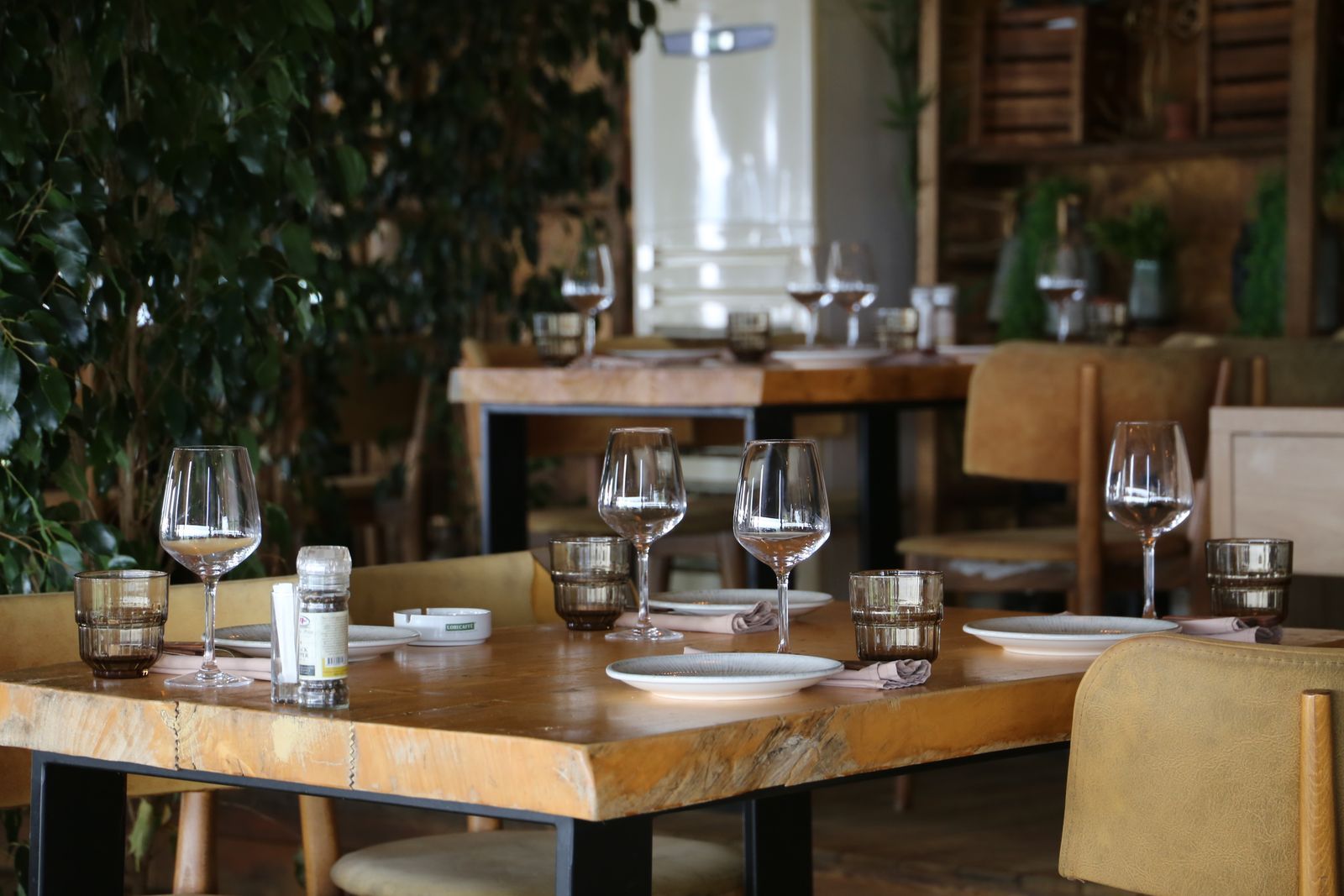 A laid table for two in the Palm Court restaurant, with candlelight and a view through the arched glazing