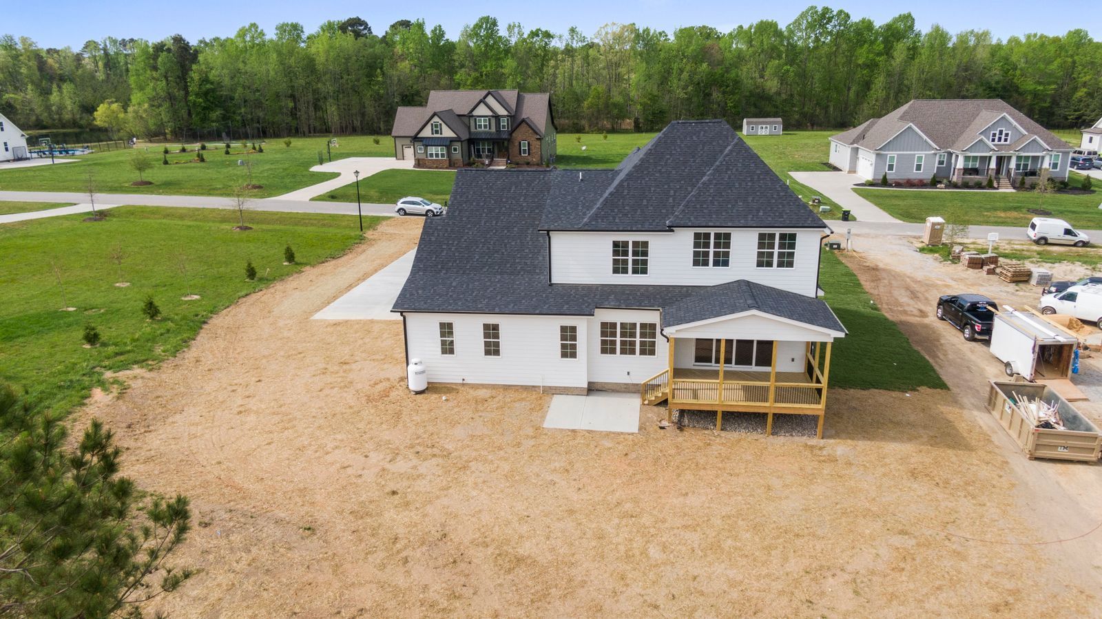 An aerial view of a newly built detached house on a large plot at the edge of a housing development