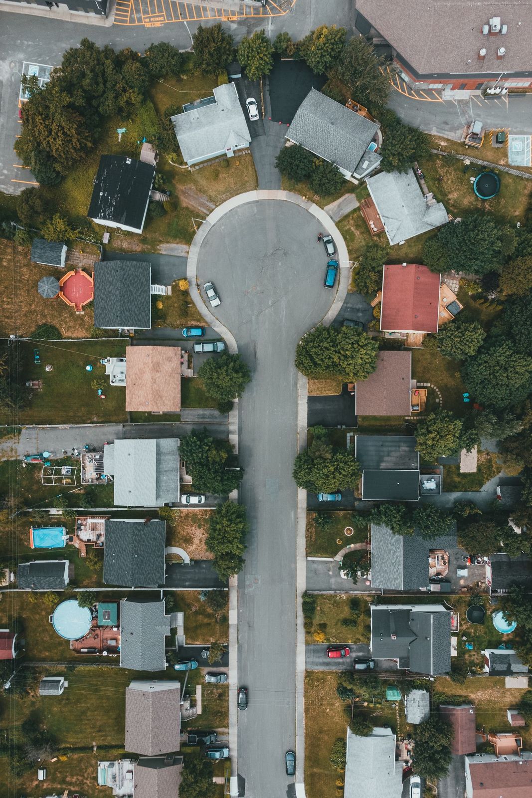 A residential street photographed from directly above, with detached houses and driveways