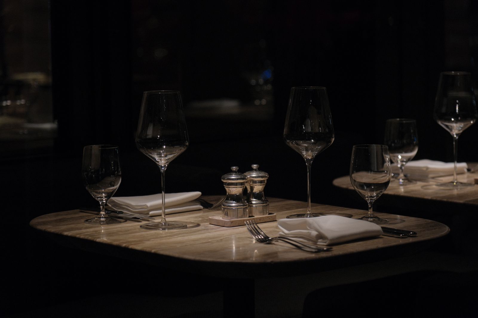 The candle-lit dining room at Oliva, tables set for the evening service